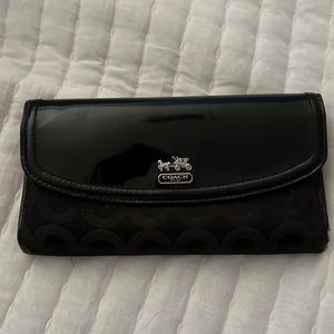 Classic Coach black wallet with patent leather fold.